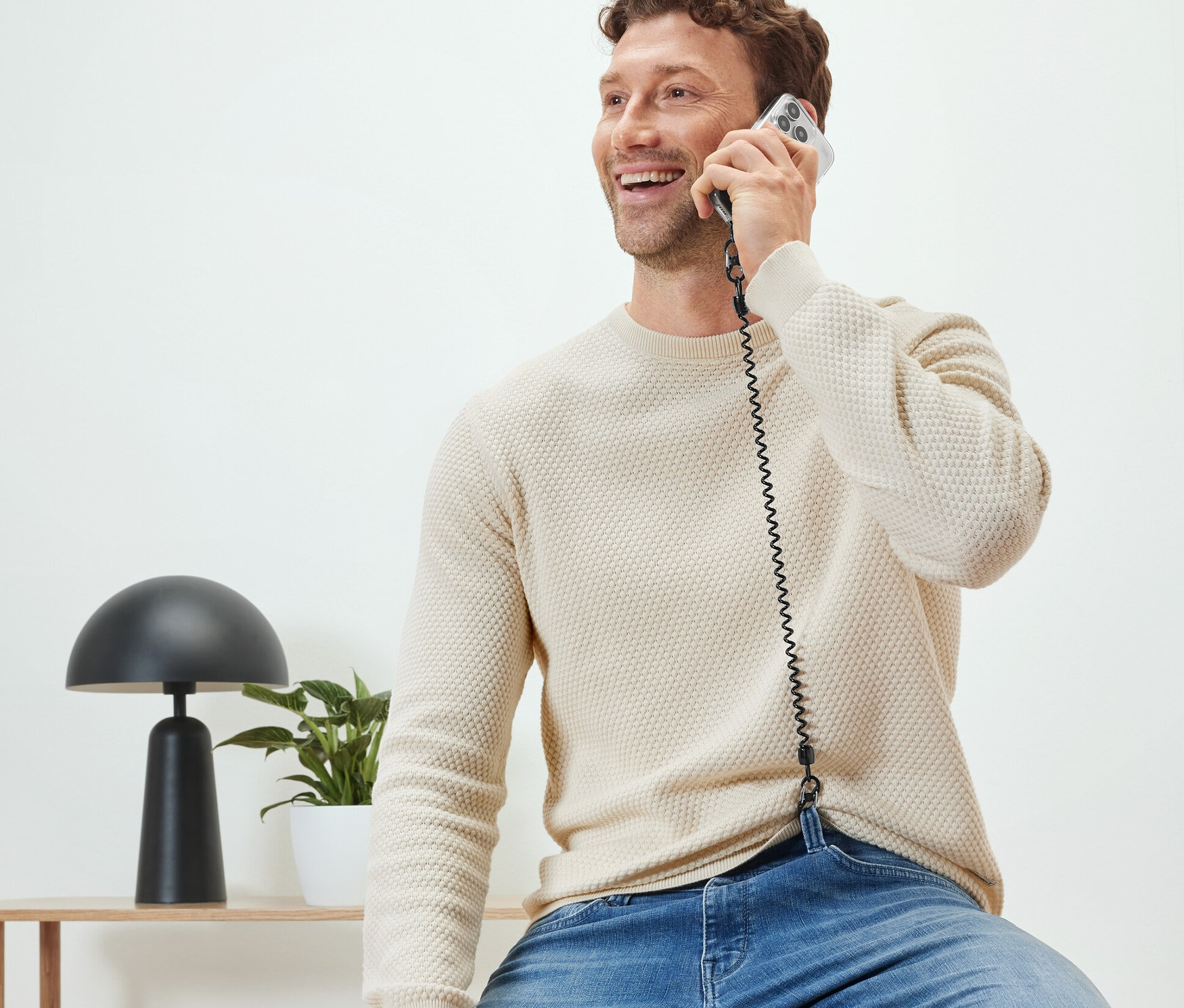 Egy férfi ül és telefonál egy biztonsági lánccal a mobiltelefonjához.