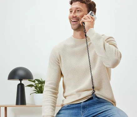Egy férfi ül és telefonál egy biztonsági lánccal a mobiltelefonjához.