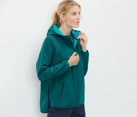 Nő felveszi a softshell dzsekijét.