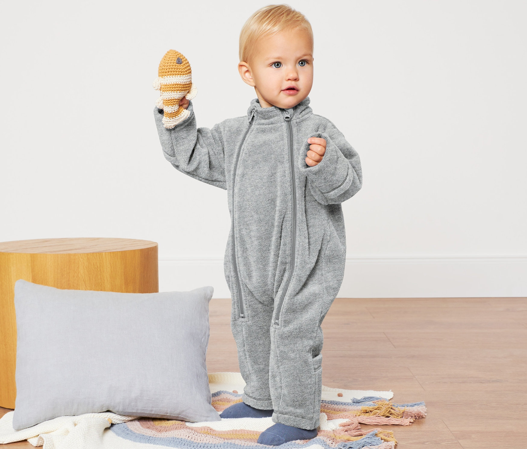 Kisgyermek horgolt halat tart, szürke baba polár kezeslábast visel.