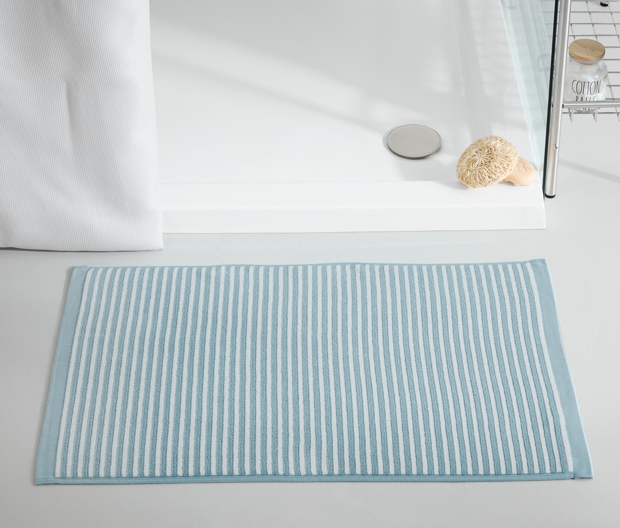 Kék fürdőszobaszőnyeg a zuhanykabin előtt.