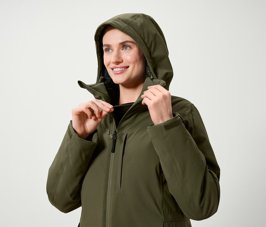 Nő állítja egy olívazöld kabát kapucniját.