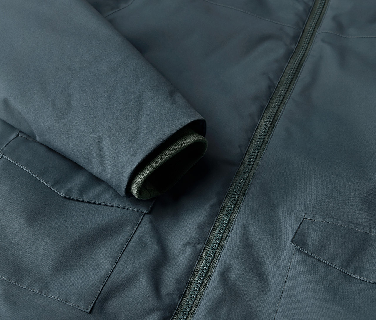 Egy gyermek téli parkakabát részlete zsebbel és cipzárral.