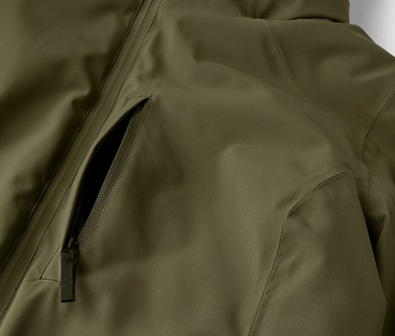 Egy olívazöld kabát részlete cipzáras zsebbel.