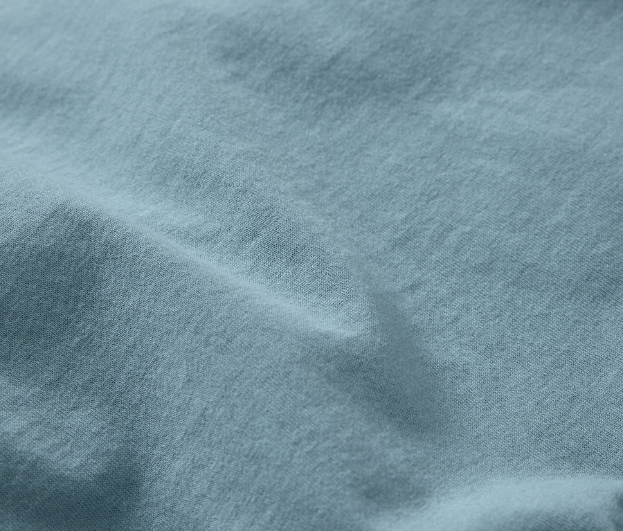 Egy világoskék, finom textúrájú, ráncos anyag közeli képe.