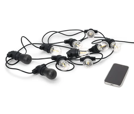 Egy fekete kültéri LED-es fényfüzér 2 Bluetooth® hangszóróval egy mobiltelefon mellett fekszik fehér háttéren.