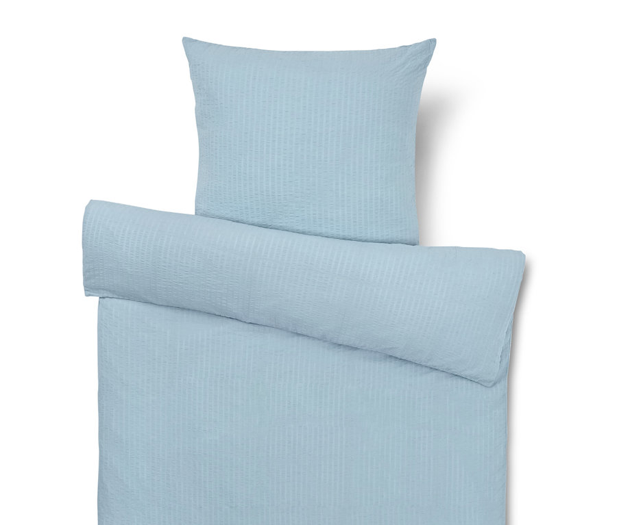Világoskék ágynemű párnával, paplannal és hengerpárnával.