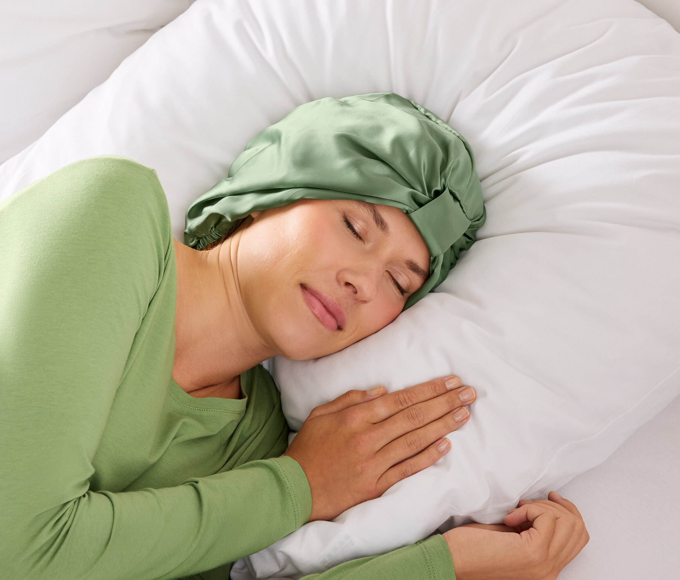 Nő alszik zöld hajpánttal egy fehér párnán.