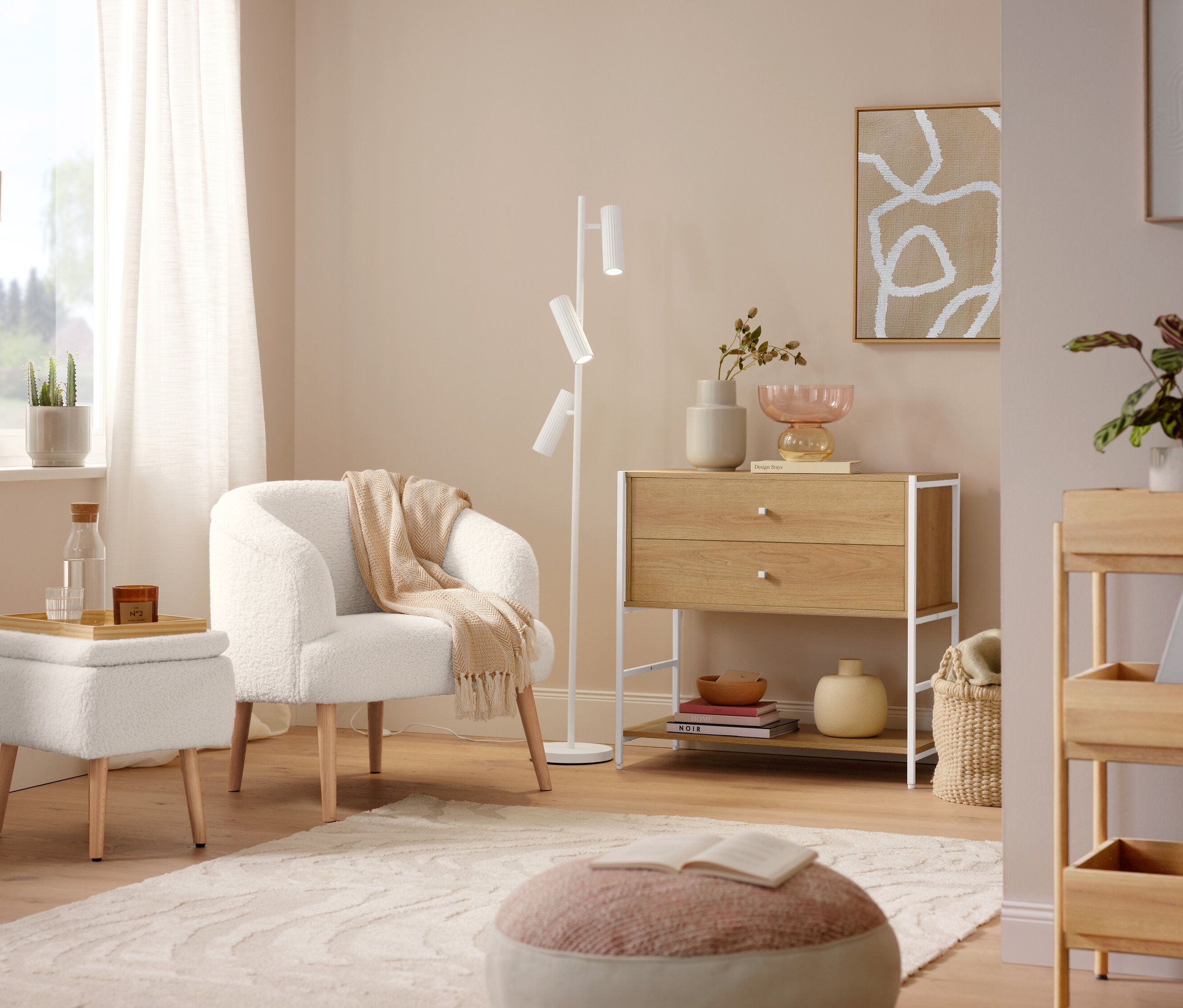 Egy buklé fotel fa lábakkal áll a Trio »Soka« állólámpa mellett. A padlón egy szürke »Cosmo «Waves szőnyeg található.