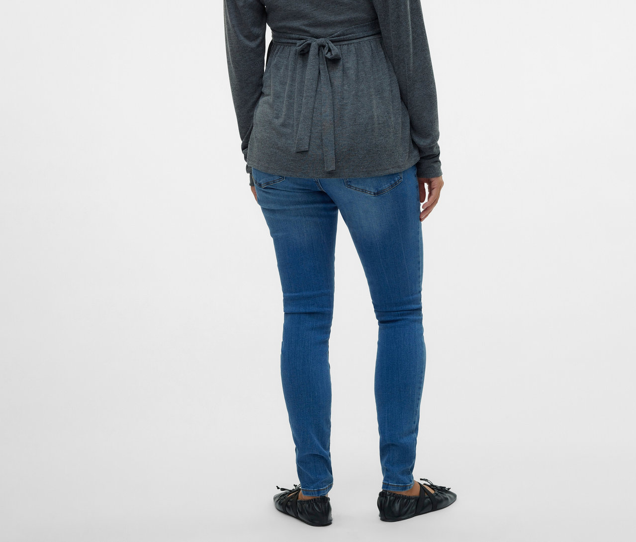 Hátulnézet egy szürke, megkötős blúzt és MAMALICIOUS kismama farmernadrágot viselő nőről, fehér háttér előtt.