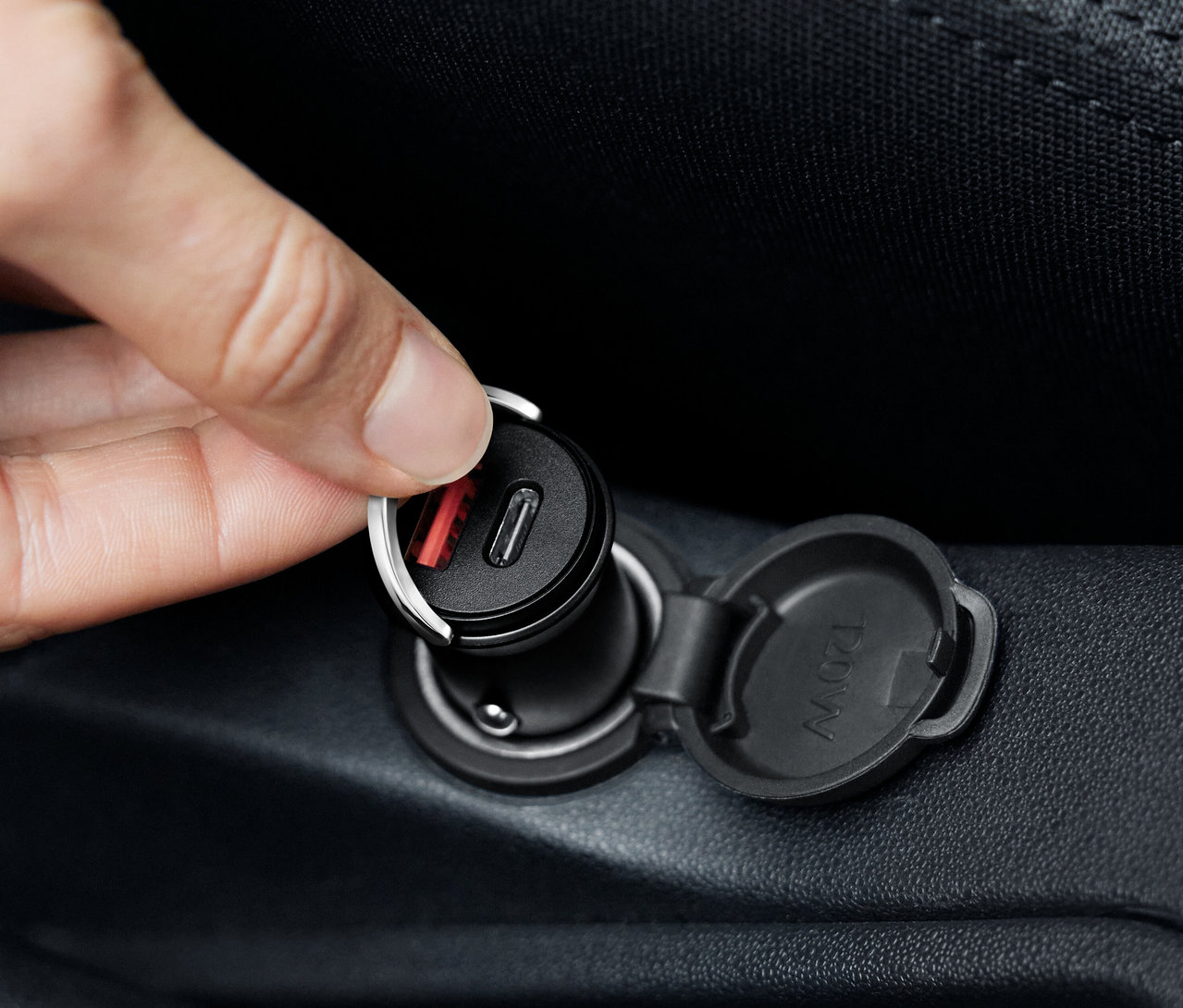 Kéz csatlakoztat egy fekete USB-C autós töltőt.