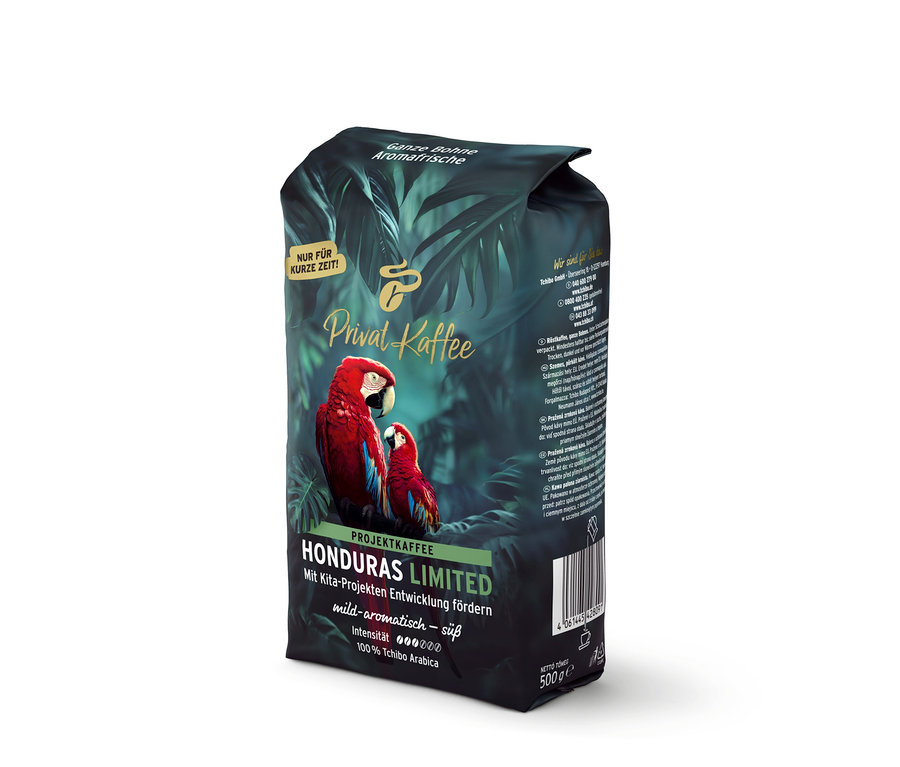 Sötétzöld Privat Kaffee Limited Edition Honduras kávécsomagolás két vörös arapapagájjal és trópusi levelekkel. Felirat: „Egész szemes, aromásan friss, enyhén aromás – édes, 100% Tchibo Arabica“.