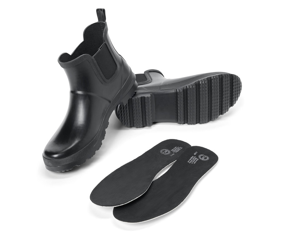 Két fekete gumicsizma és két fekete cipőbetét fehér háttéren.