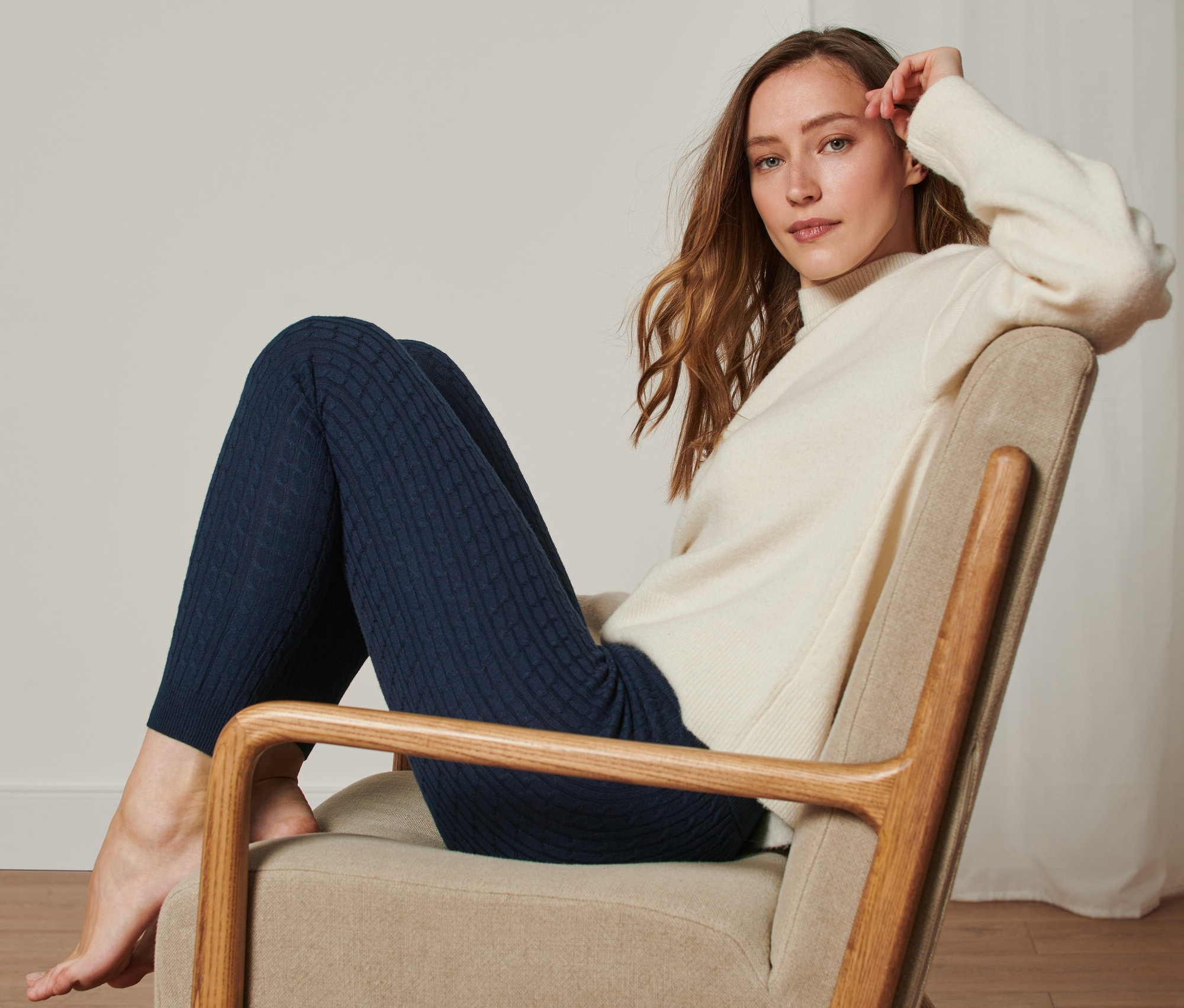 Nő ül a székben és kötött leggingset visel.