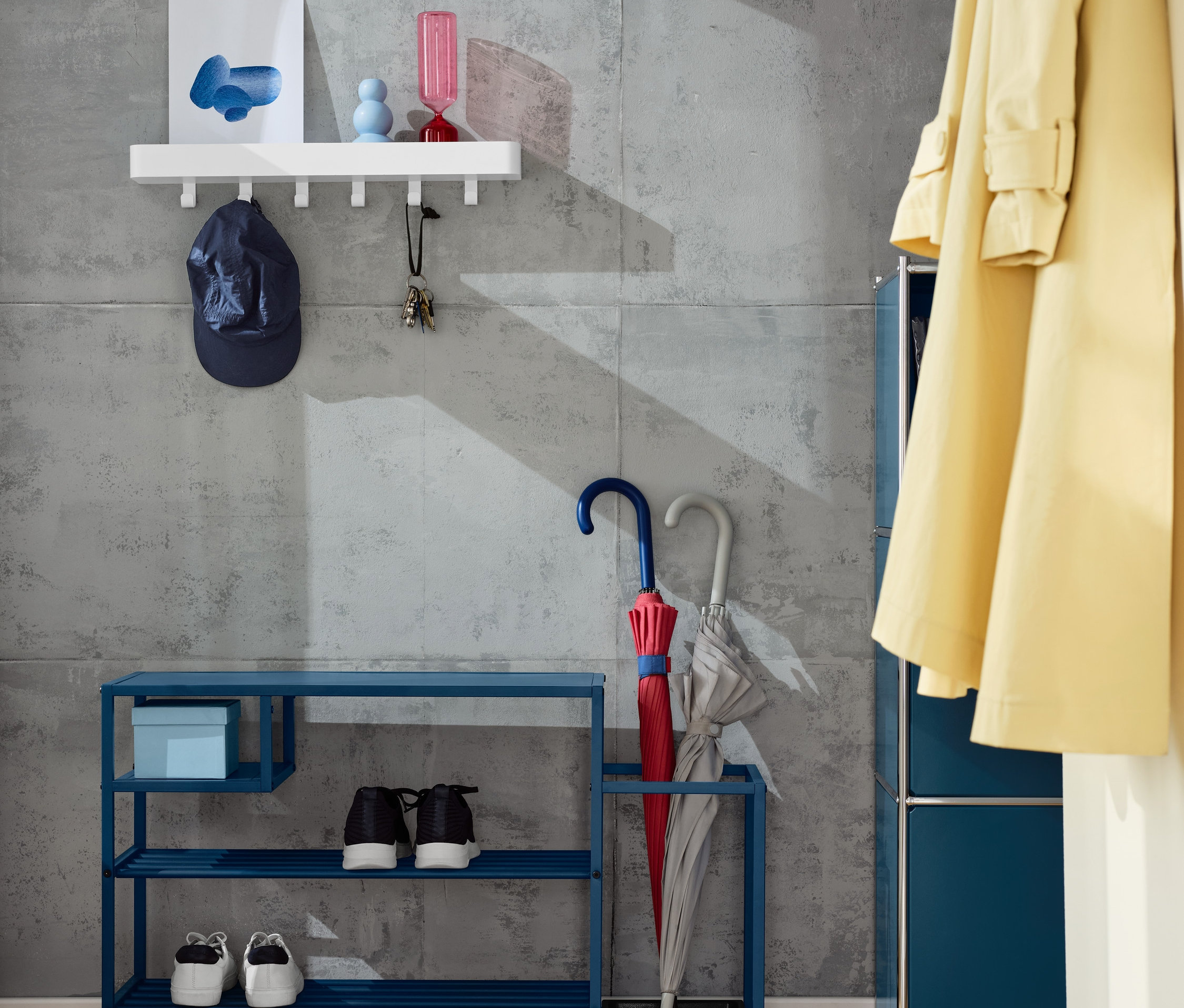 A falon fogas tárolóval, alatta kék cipőspolc esernyőtartóval.