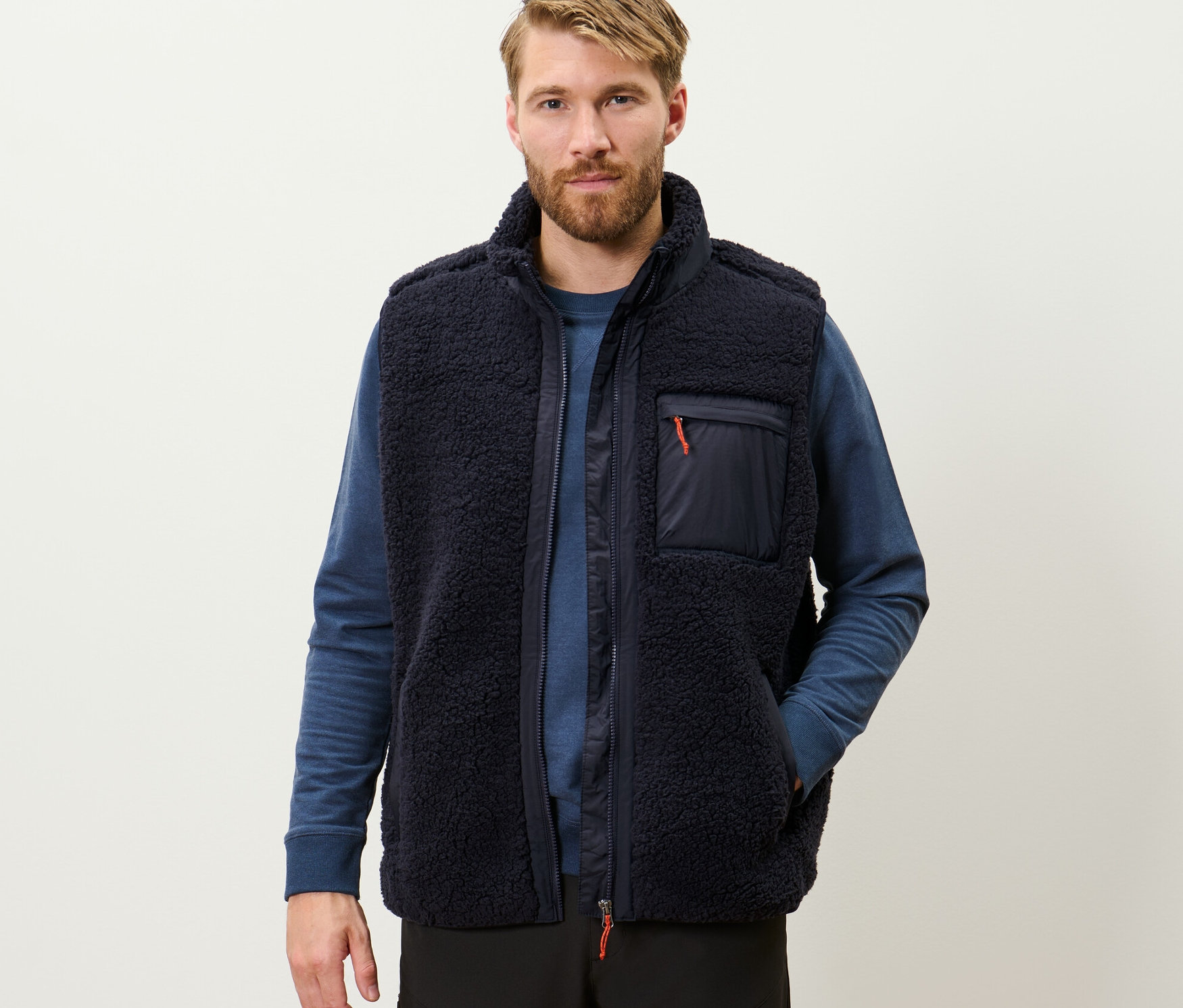 Férfi sötétkék plüssmellényt visel.