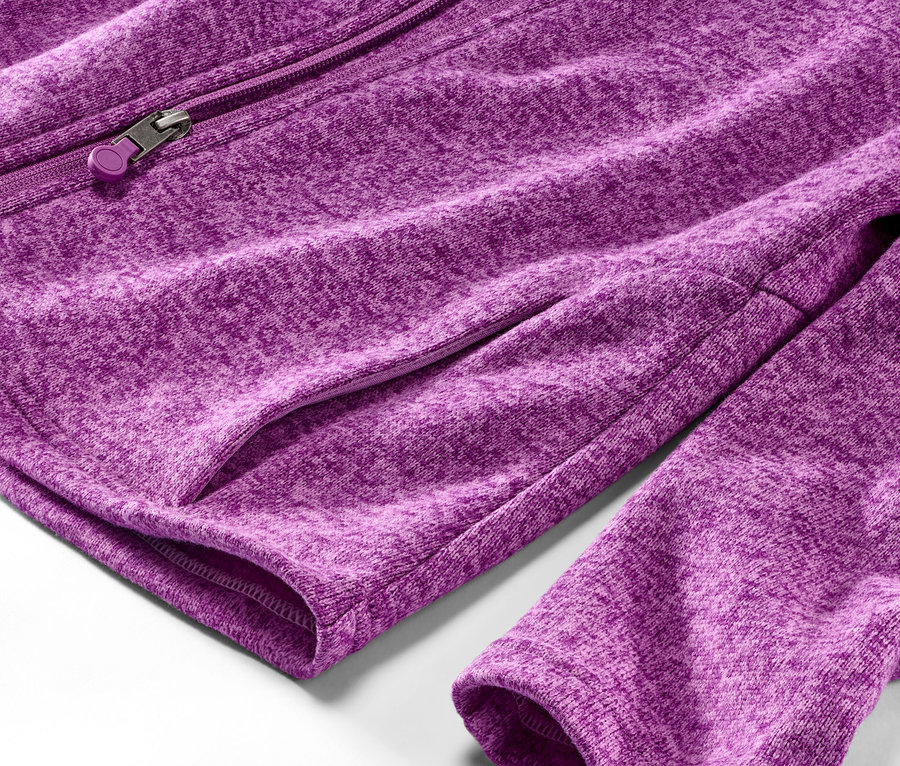 Egy málna színű kötött polárfelső részletgazdag képe, zsebbel és cipzárral.