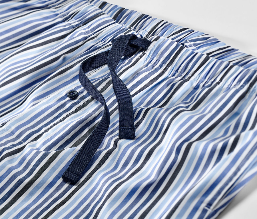 Egy csíkos, rövidnadrágos pizsama részlete kék és fehér színben, húzózsinórral.