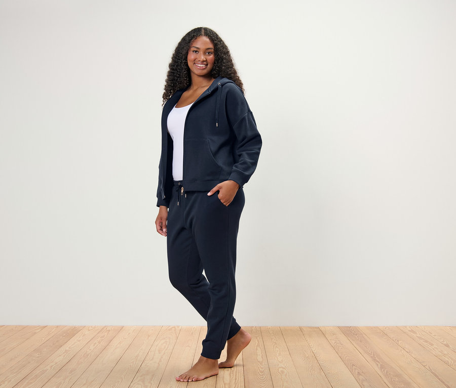 Nő áll és pózol egy sötétkék női szabadidő szettben.