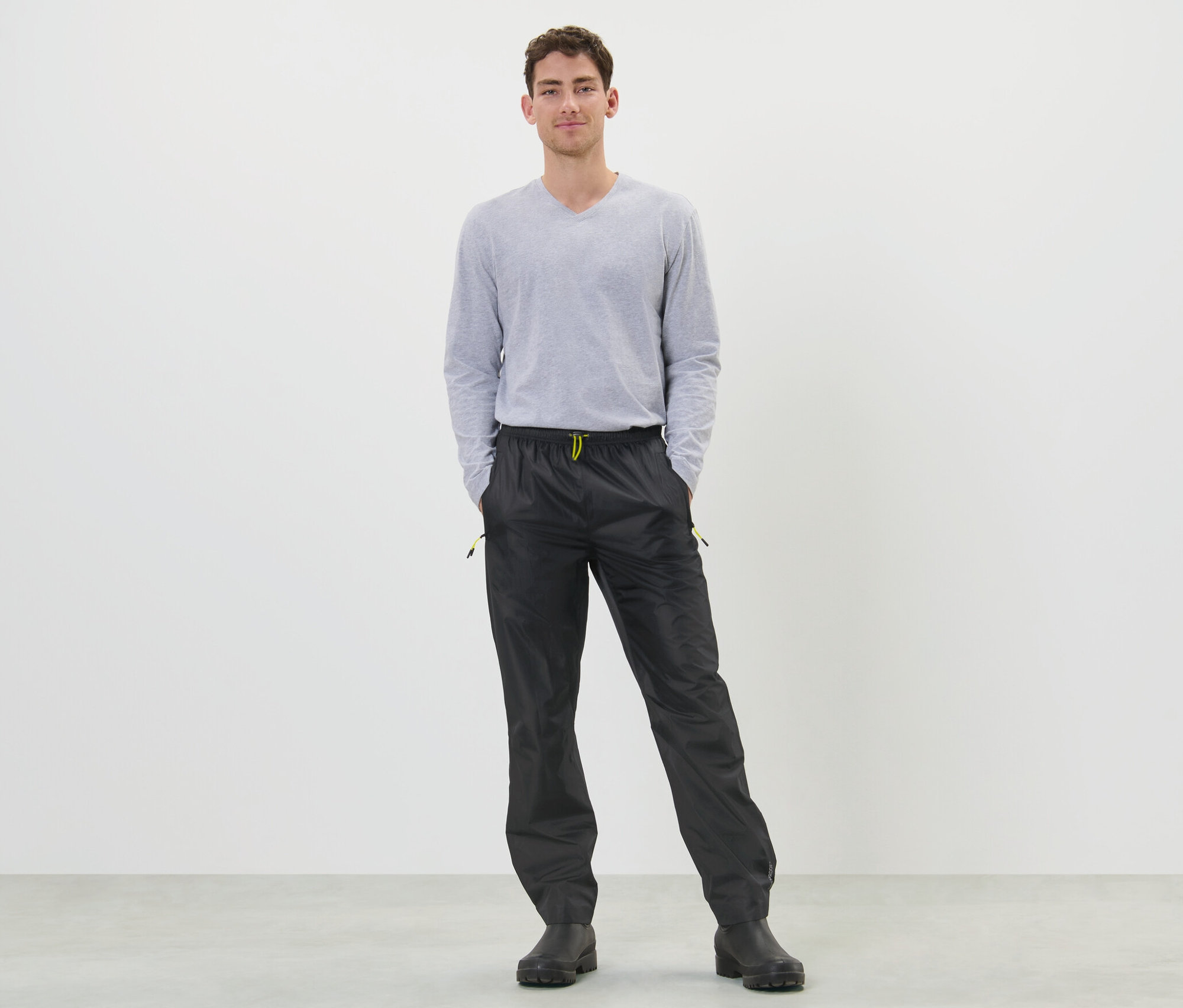 Férfi áll fekete esőnadrágban.