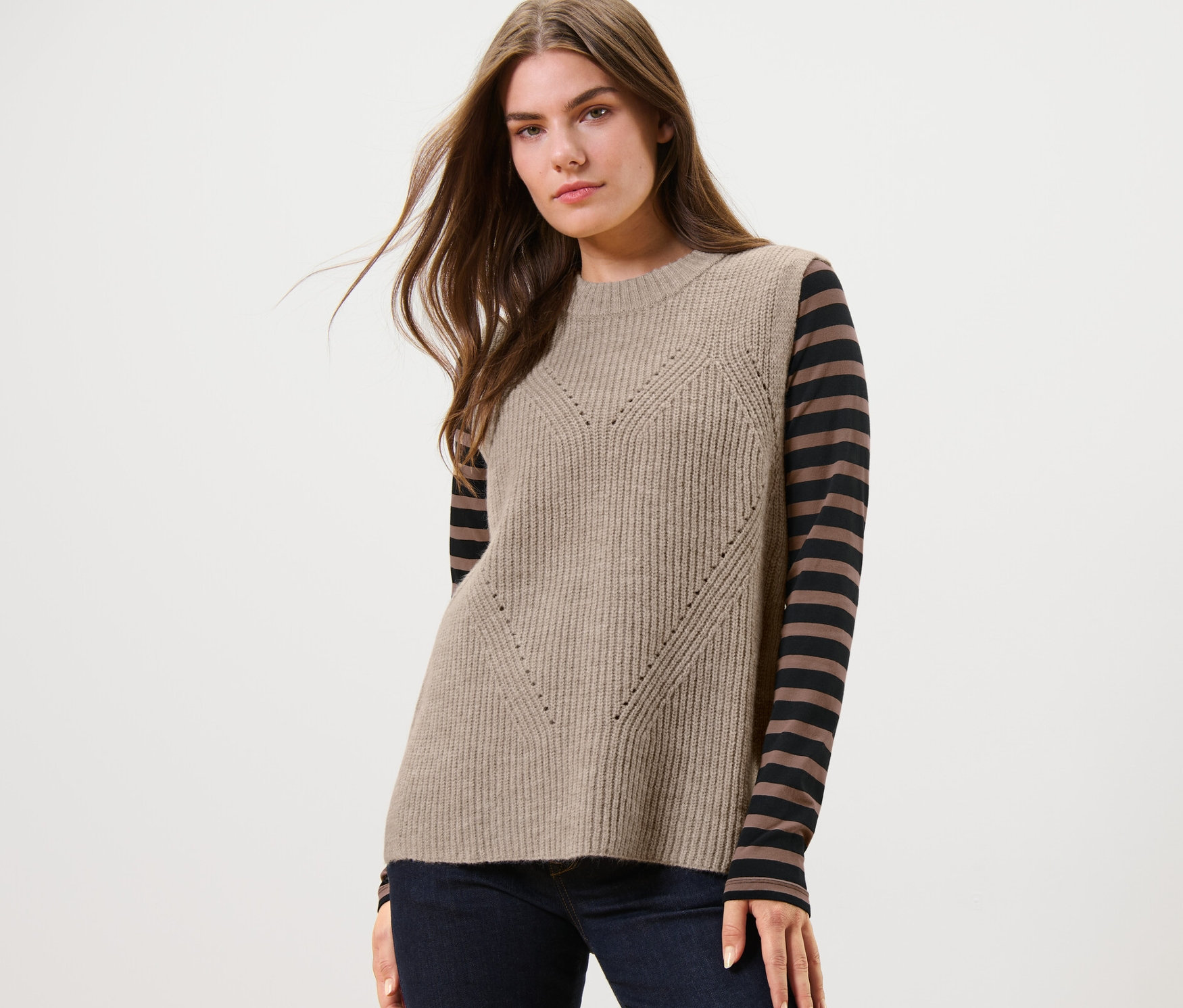 Nő visel egy melírozott bézs kötött mellényt.