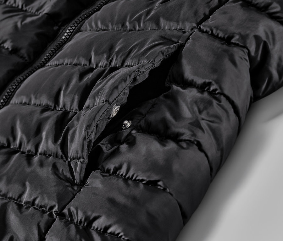 Egy fekete, steppelt mellény részlete zsebbel.