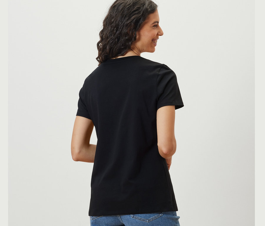 Nő néz a válla fölött, fekete pólót visel.