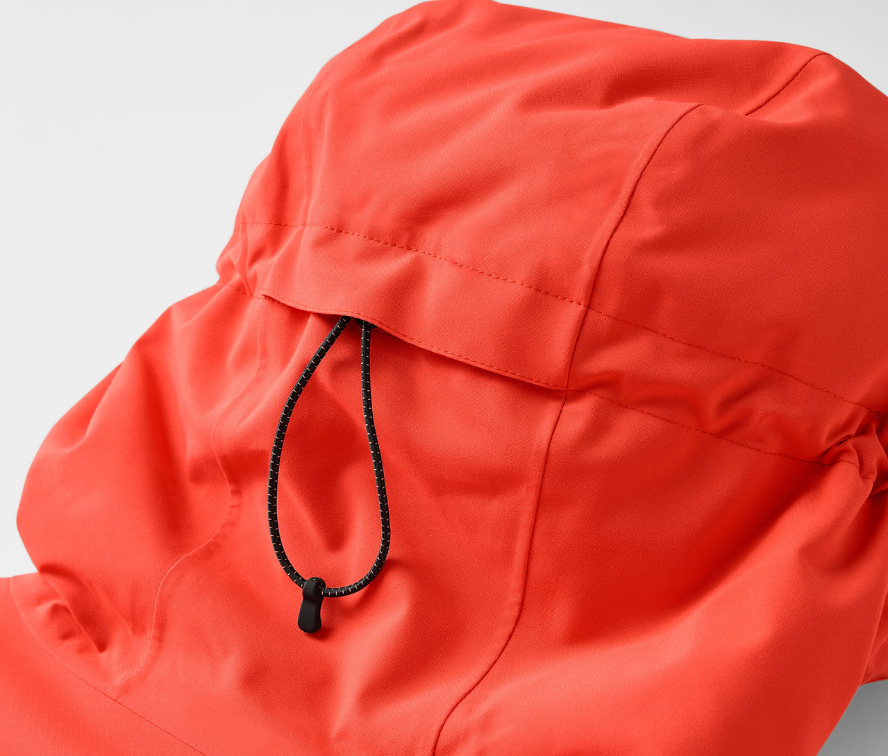 Egy narancssárga kabát kapucnijának részlete húzózsinórral.