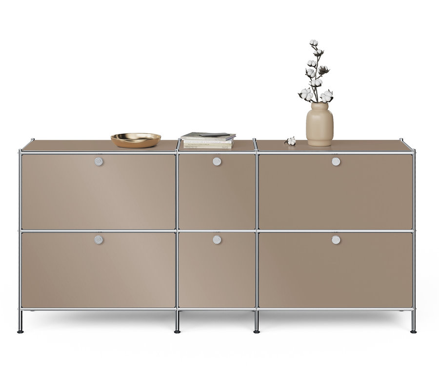 Szürkésbarna komód hat ajtóval, a tetején egy arany tál, egy könyv és egy váza virágokkal.