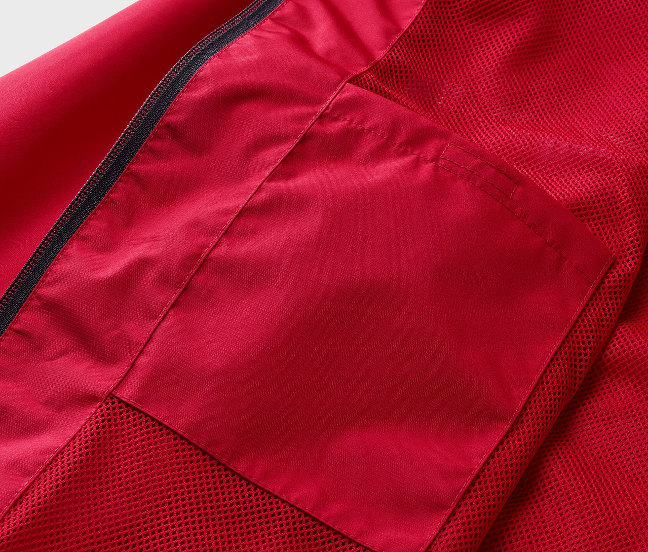 Egy piros esőkabát részlete, zsebbel.