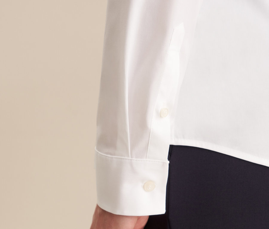 Egy fehér, hosszú ujjú, gombos mandzsettával ellátott Seidensticker slimfit blúz részlete.