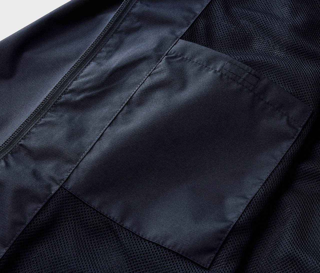Egy sötétkék esőkabát részlete zsebbel.
