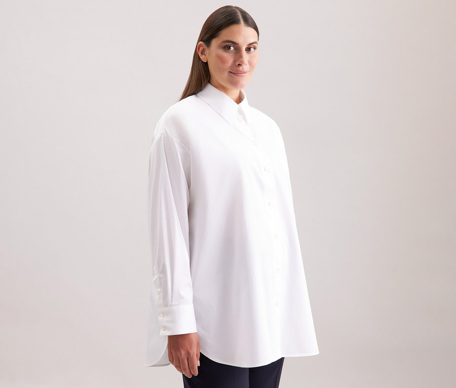 Nő visel egy fehér Seidensticker túlméretes hosszú ingblúzt.