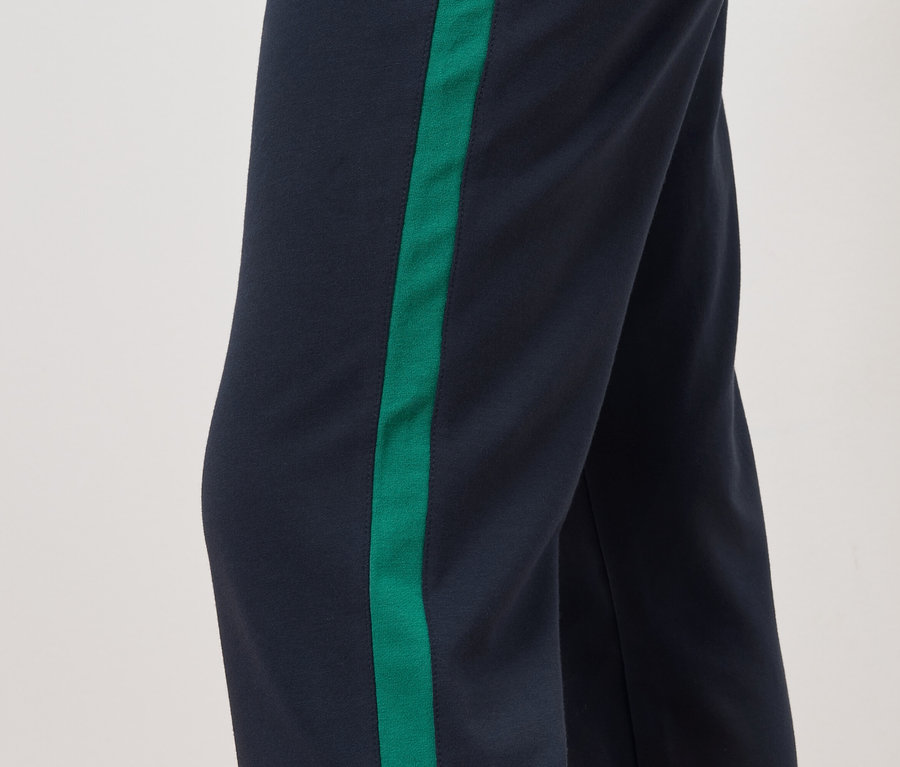 Nadrág részlete sötétkék háttérrel és zöld csíkkal az oldalán.