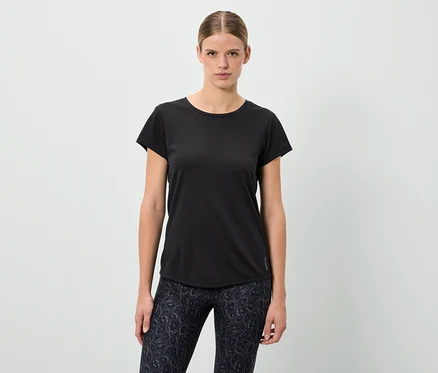 Egy nő áll, fekete pólót és mintás leggingset visel.