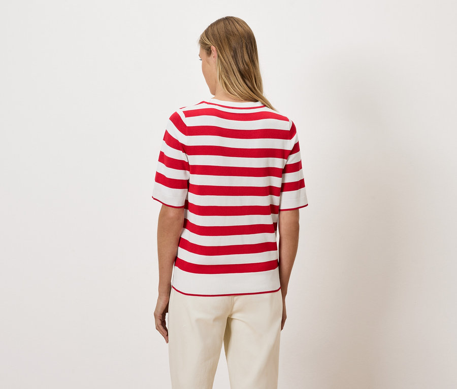 A hátulról látható nő piros-fehér csíkos felsőt visel.