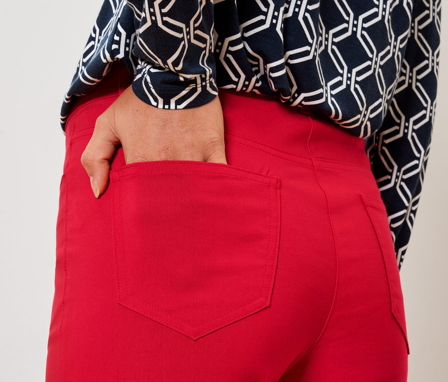 Nő a kezét a piros nadrág hátsó zsebébe teszi.