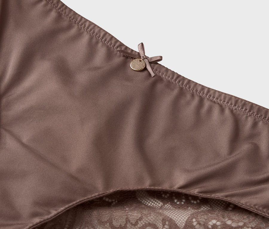 Közelkép egy csipkés szegélyű és masnis barna alsóneműről.