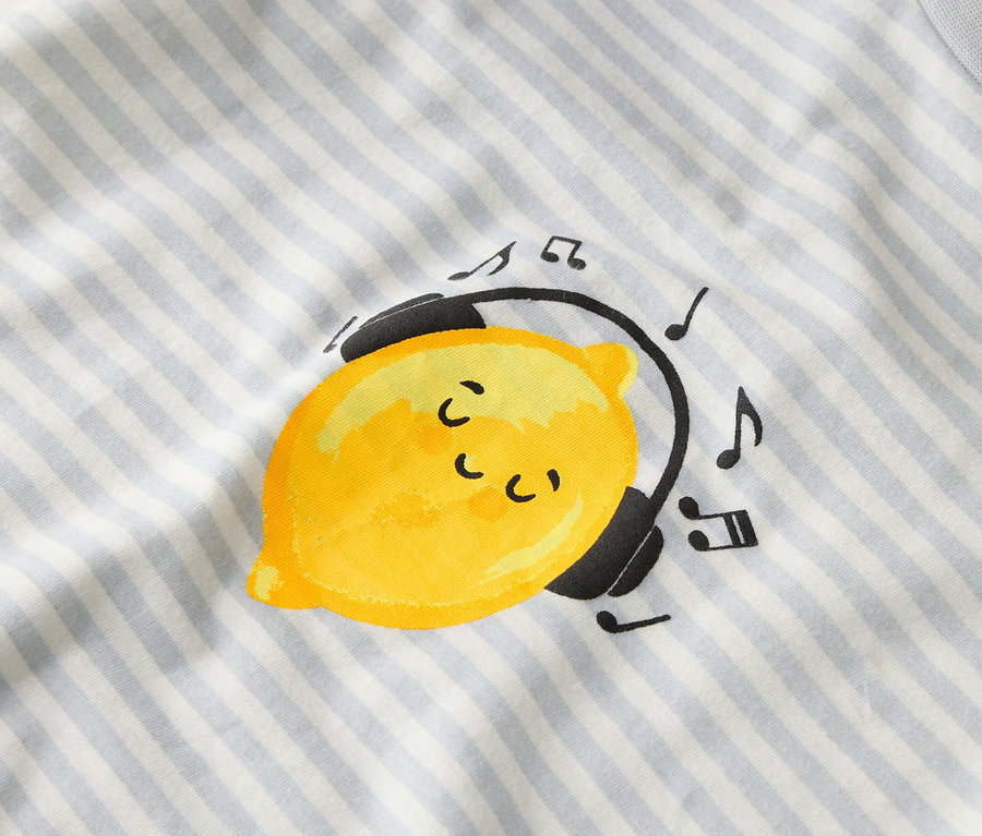 Csíkos anyagon egy sárga citrom látható fejhallgatóval és hangjegyekkel.