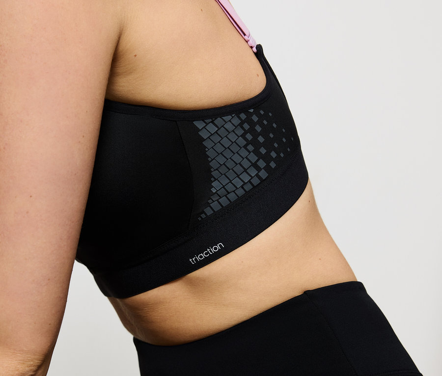 Egy fekete Triaction sportmelltartót és leggingset viselő nő közeli képe.