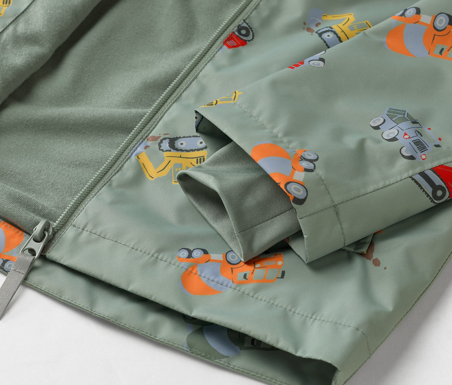 Közeli kép egy olívazöld, építőipari jármű mintás kabátról, részben cipzárral nyitva.