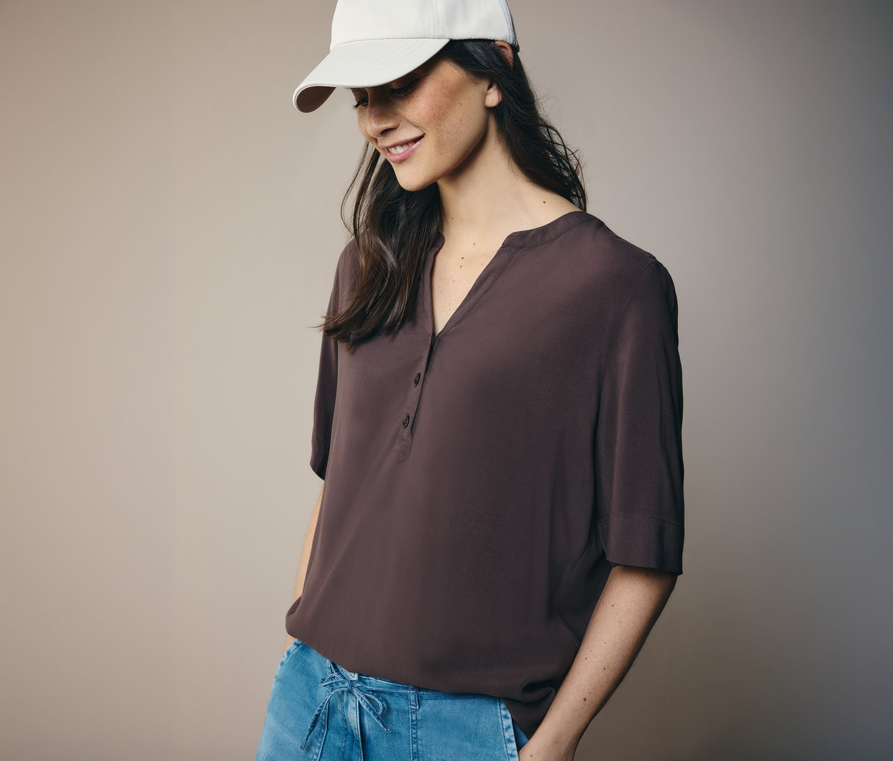 Nő fehér sapkában és barna CECIL tunikablúzban.