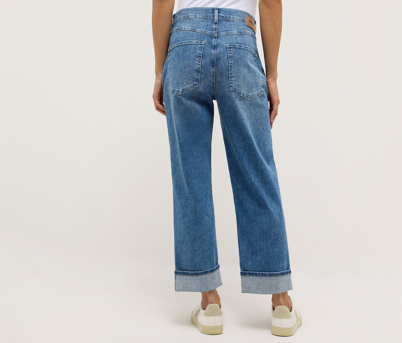 Hátulról látható személy, aki Angels denim »Liberta« farmert és krémszínű cipőt visel.