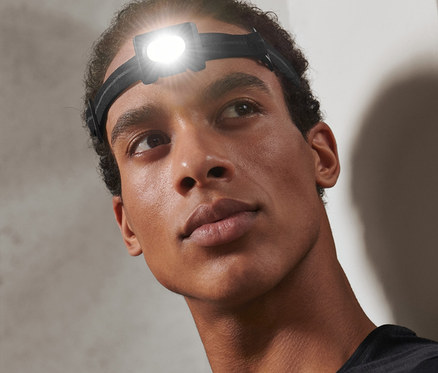 Férfi néz felfelé, a fején egy mini fekete akkus fejlámpa van.