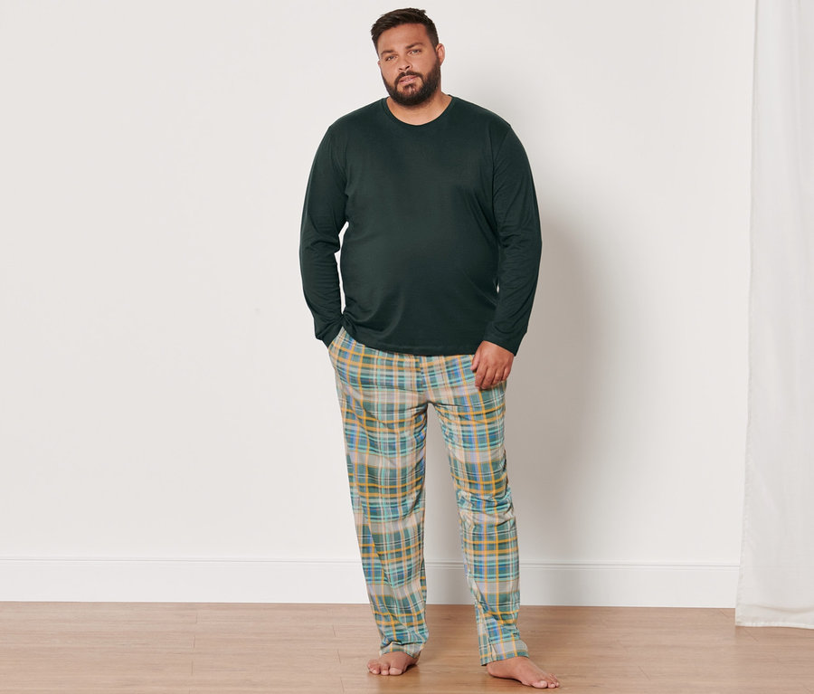 Férfi hosszú ujjú pizsamában és kockás nadrágban áll egy szobában.