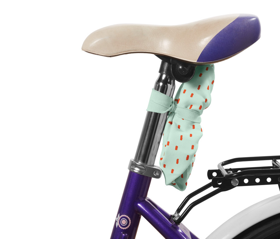 Piros pöttyös gyerek kerékpáros üléshuzat rögzítve egy kerékpár nyergéhez.