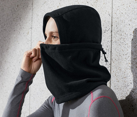 Nő igazítja a fekete mikropolár kámzsát a fején.