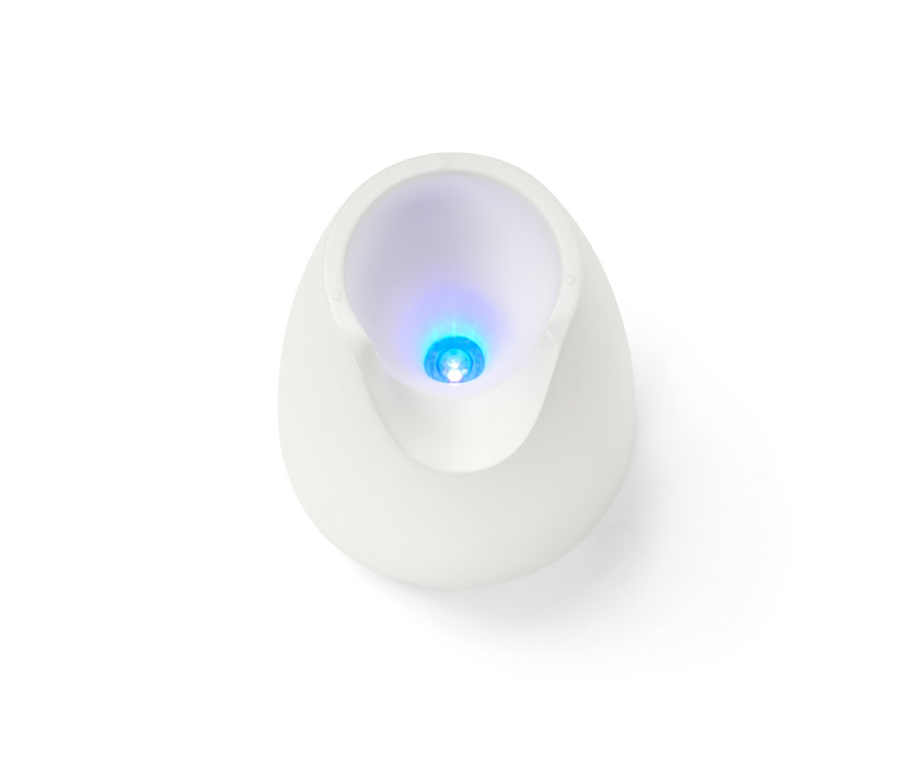 Egy fehér UV lámpa felülnézeti közeli képe egy manikűr- és pedikűrkészletből, kék fénnyel világít.