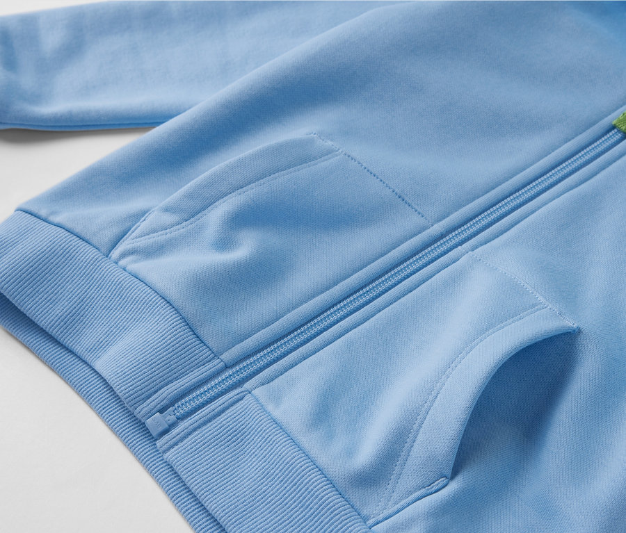 Egy világoskék, belül bolyhos, cipzáros, zsebes kisfiú szabadidőfelső közelképe.