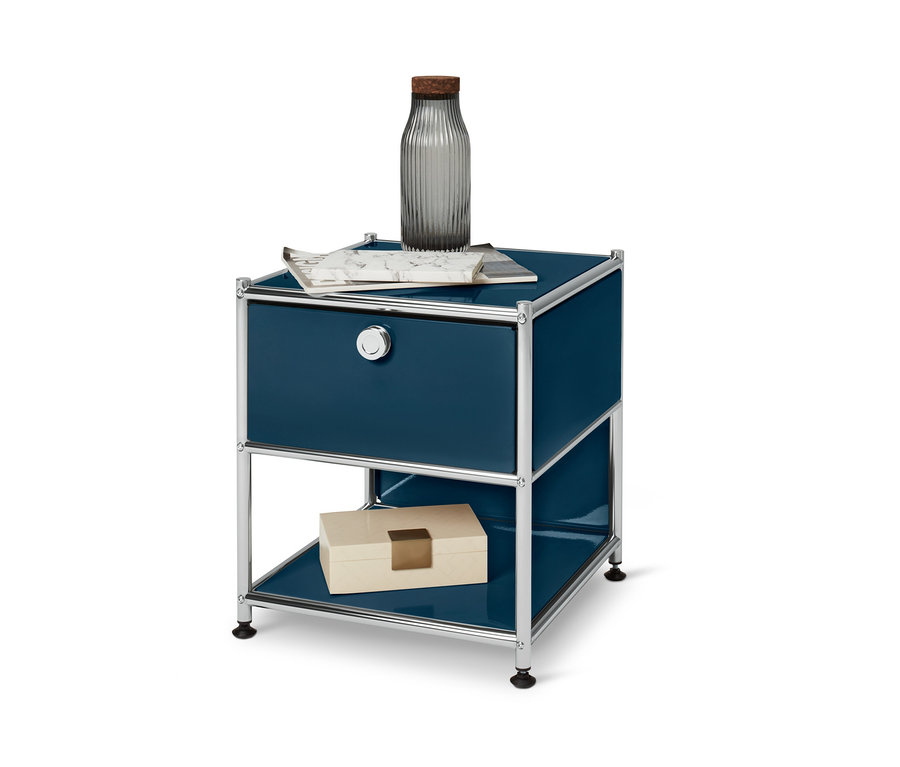 Kék »CN3« fém éjjeliszekrény 1 fiókkal. A tetején váza és folyóirat, alul pedig egy doboz található.